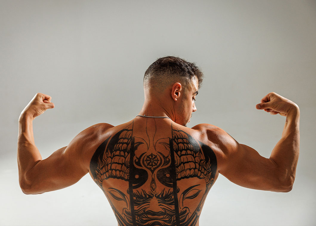 El coach flexiona los brazos mostrando su espalda tatuada.